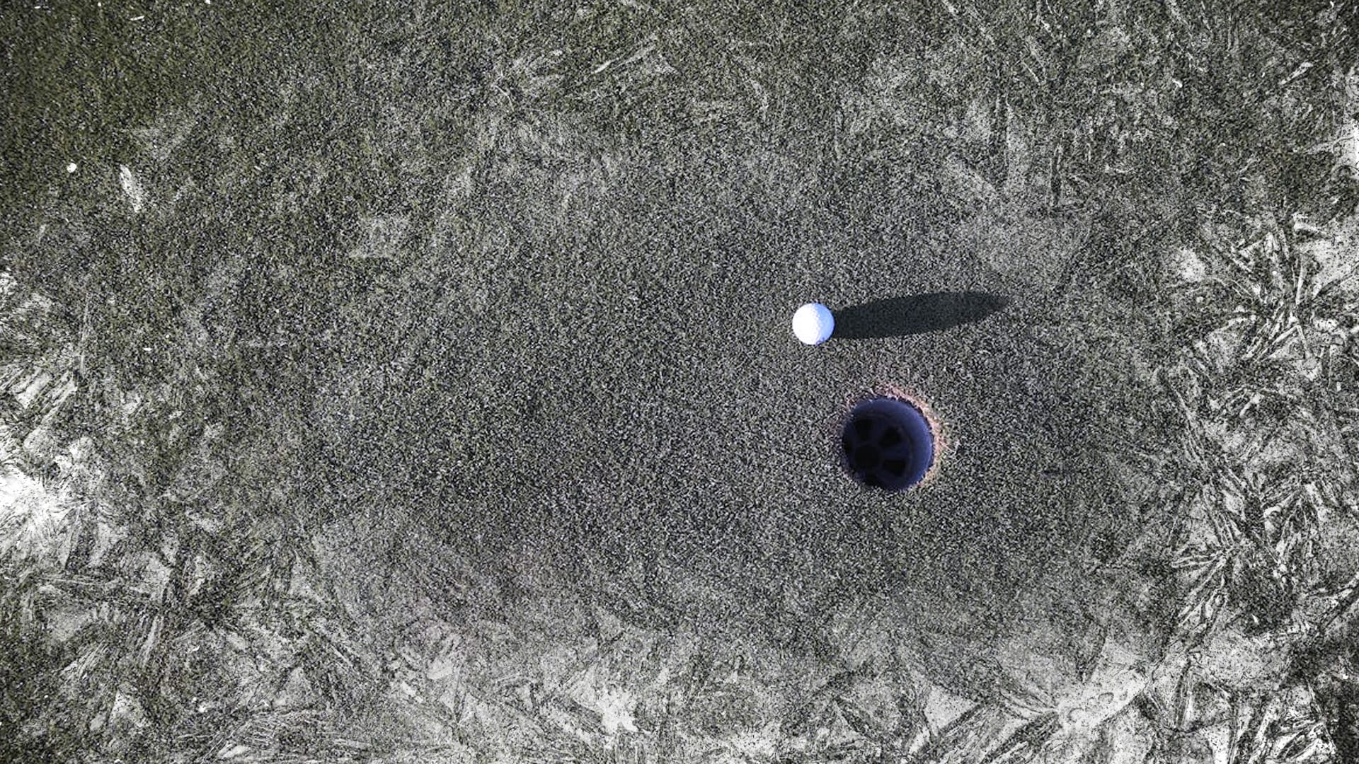A frost-covered golf hole with a golf ball sitting close by