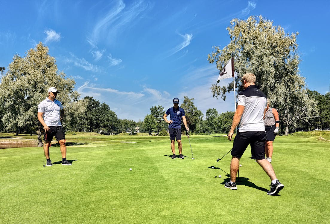 A group of golfers standing on a green with balls in play