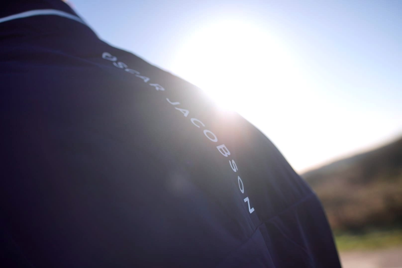 Image shows the Oscar Jacobson logo on the back of the Laguna jacket with the sun blooming in the bckground.