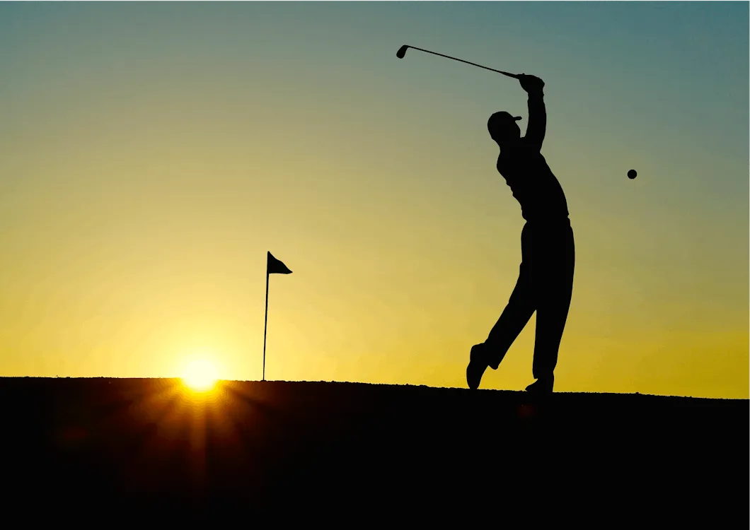 Golfer completing his swing silhouetted against the sun